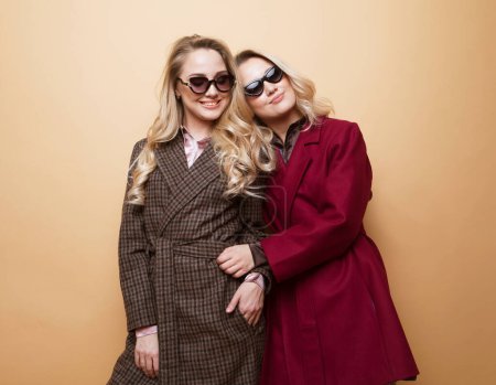 Téléchargez les photos : Fashion and beauty concept: Two young women posing in nice clothes, coat, sunglasses. Sisters, twins. Spring fashion photo. - en image libre de droit