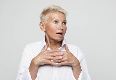 Foto de Old people, modern lifestyle, body language concept. Close-up portrait of shocked mature woman in white shirt isolated on grey background - Imagen libre de derechos