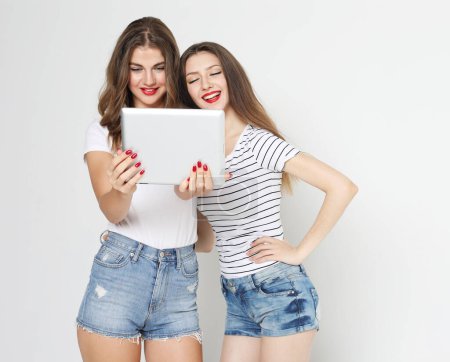 Foto de Estilo de vida, tehnología y concepto de personas: Dos amigas jóvenes con tableta digital - Imagen libre de derechos
