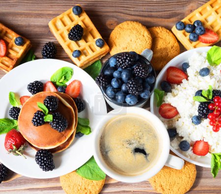 Foto de Waffles with blueberries and raspberries on plate. Cottage cheese, Coffee and berries on wooden background. Flat lay. Top view. - Imagen libre de derechos