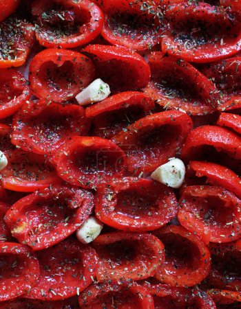 Photo for Tomatoes lie on a baking sheet, ready to bake. Sun-dried tomatoes with garlic. Food background. - Royalty Free Image