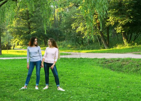 Photo for Mother and adult daughter in the park. Two beautiful happy women with long curly hair. Full length portrait. Summer day in the park. - Royalty Free Image