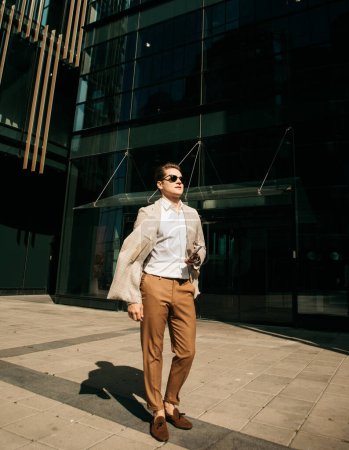 Foto de Business, people and success concept: Handsome man in fashinable outfit walking near modern office, summer time - Imagen libre de derechos