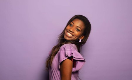 Foto de Happy Afro woman smiling, has good mood isolated on studio purple background. Excited african american female. Positive life concept. - Imagen libre de derechos