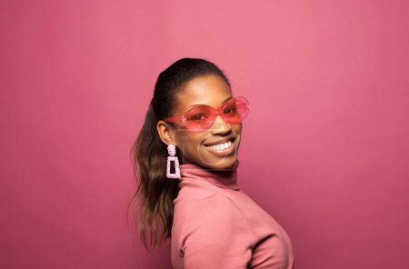 Foto de Mujer afro feliz sonriendo, tiene buen humor aislado en el estudio de fondo rosa. Emocionada mujer afroamericana. Concepto de vida positiva. - Imagen libre de derechos