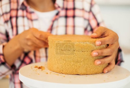 Téléchargez les photos : Beautiful young woman cuts cake cakes with a knife on the kitchen, - en image libre de droit