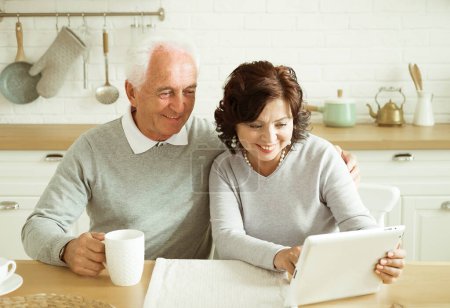 Photo for Lifestyle, tehnology and old people concept. Elderly couple, husband and wife using digital tablet at home, kitchen room. - Royalty Free Image