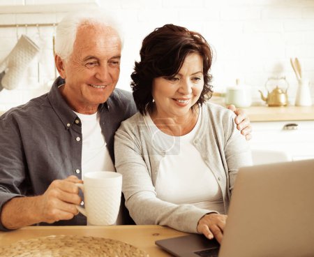 Photo for Elderly couple, husband and wife using digital tablet at home, kitchen room - Royalty Free Image
