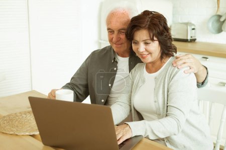 Téléchargez les photos : Elderly couple, husband and wife using digital tablet at home, kitchen room - en image libre de droit