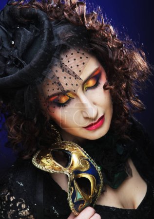 Foto de Beautiful woman with bright makeup and hat with veil holding venetian mask, close up portrait. - Imagen libre de derechos