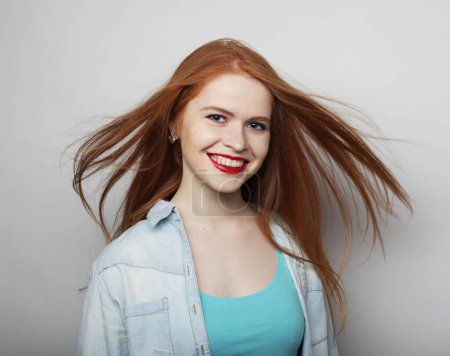 Téléchargez les photos : Beautiful young happy woman with long flowing red hair over grey background - en image libre de droit