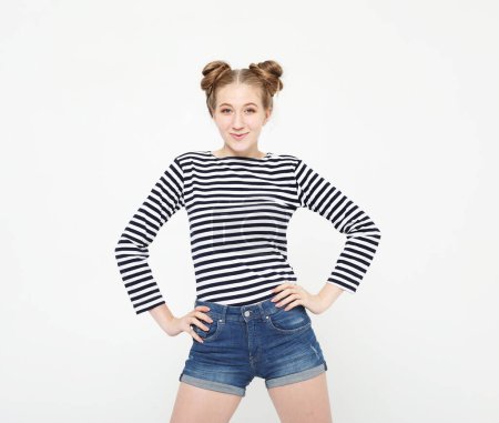 Foto de Funny young woman smiling and standing with her hands on her hips over light grey color background - Imagen libre de derechos