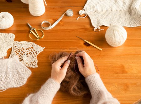 Foto de Primer plano de las manos femeninas tejiendo bufanda de lana de color marrón. Vista superior. Independiente. Hobby.. - Imagen libre de derechos