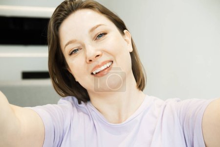 Photo for Good mood woman with expansive smile taking selfie on mobile phone at home. Lifestyle concept. - Royalty Free Image
