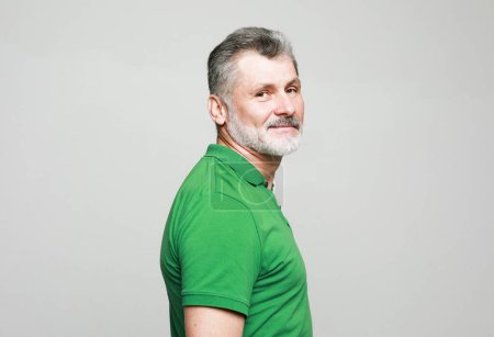 Téléchargez les photos : Portrait of senior elderly caucasian old handsome man wearing green t-shirt isolated on grey color background. - en image libre de droit