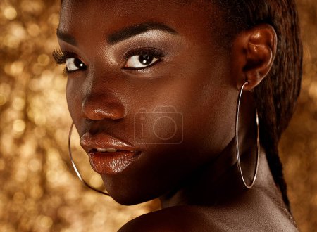 Foto de Beautiful young African woman with bright make up posing against a gold background. - Imagen libre de derechos