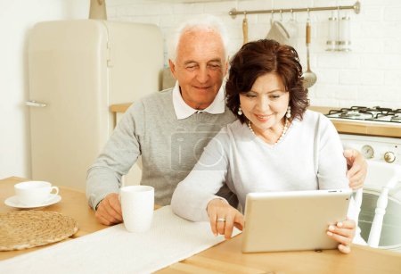Téléchargez les photos : Elderly husband and wife using digital tablet at home, happy family - en image libre de droit