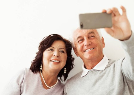 Téléchargez les photos : Head shot portrait happy elderly couple taking selfie, having fun with phone cam, smiling aged wife and husband hugging, looking at camera, posing for pictures, aged man vlogger recording video - en image libre de droit