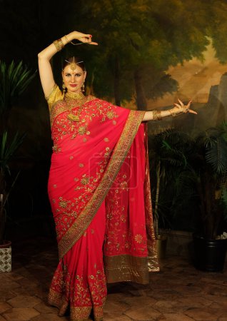 Foto de Beautiful young woman in traditional sari clothing with bridal makeup and jewelery. Gorgeous bride traditionally dressed. Girl bollywood dancer in Sari, full height. - Imagen libre de derechos