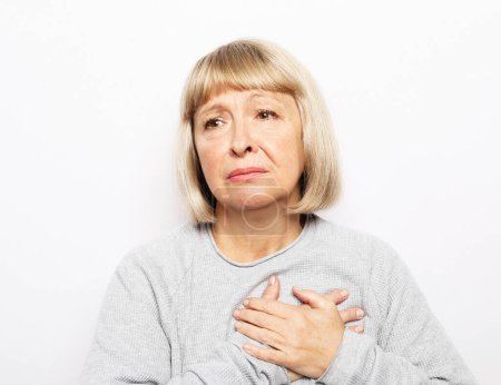 Photo for Lifestyle, health and old people concept: An elderly woman holds her hands near her heart, her heart hurts, the old woman is experiencing exciting emotions - Royalty Free Image