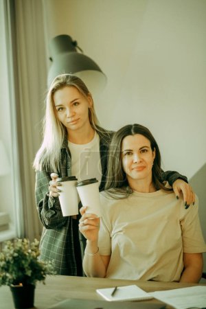 Téléchargez les photos : Two female colleagues enjoying coffee break time, discussing working issues during in office. - en image libre de droit
