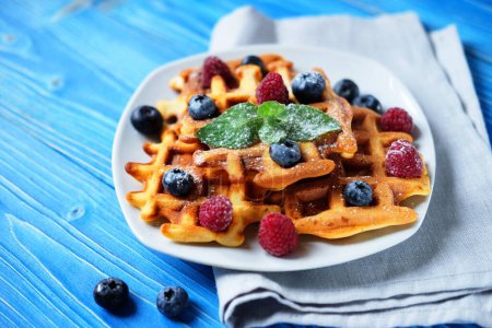 Photo for Good morning. Waffles with blueberries and raspberries for breakfast over blue wooden table. - Royalty Free Image