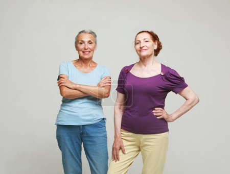 Foto de Two pretty elderly women friends on grey background. Lifestyle concept. - Imagen libre de derechos