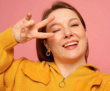 Téléchargez les photos : Close up of cheerful funny woman 40s wearing casual yellow sweater posing doing selfie shot on mobile phone put hand on head isolated on pastel pink colour background studio portrait - en image libre de droit