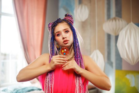 Photo for Gorgeous young woman with dreadlocks hairstyle wearing pink dress, doll style, bright make, up in the pink room. - Royalty Free Image