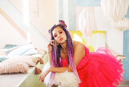Téléchargez les photos : Gorgeous young woman with dreadlocks hairstyle wearing pink dress, doll style, bright make, up in the pink room. - en image libre de droit