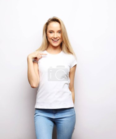 Foto de Charming smiling young woman with long blond hair dressed in a white t-shirt and jeans - Imagen libre de derechos