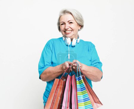 Foto de Lifestyle, shopping and old people concept: Happy mature woman with shopping bags isolated on white background - Imagen libre de derechos