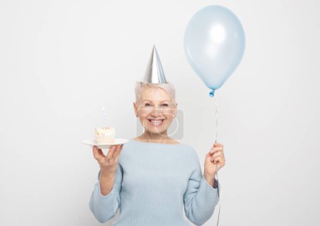 Téléchargez les photos : People, party, aging and maturity concept. Beauitful elderly female wearing conical hat celebrating birthday - en image libre de droit
