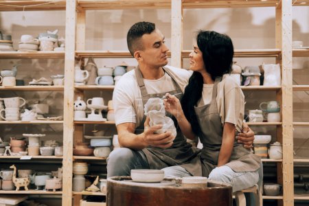 Téléchargez les photos : A young lovely couple works in a pottery workshop. Painting a vase. The concept of hobbies, lifestyle and relationships. - en image libre de droit