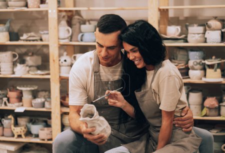 Téléchargez les photos : A young lovely couple works in a pottery workshop. Painting a vase. The concept of hobbies, lifestyle and relationships. - en image libre de droit