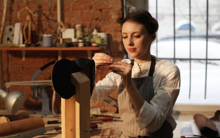 Handtaschenhandwerkerin aus Leder bei der Arbeit in einer Werkstatt. Hobby und freiberufliches Konzept.