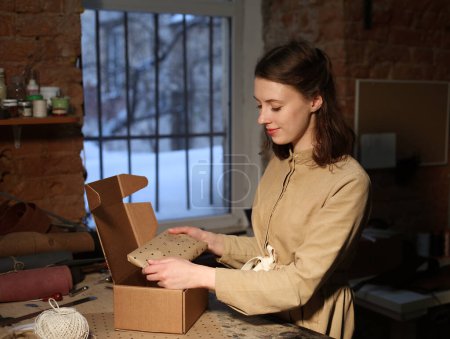 Foto de Mujer joven pliega la caja de embalaje en el taller de costura - Imagen libre de derechos