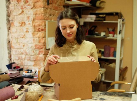 Foto de Mujer joven pliega la caja de embalaje en el taller de costura - Imagen libre de derechos
