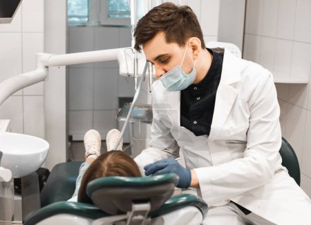 Photo for People, medicine, stomatology, technology and health care concept. Professional young male dentist working with little girl in clinic. - Royalty Free Image
