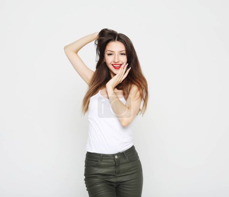 Photo for Lifestyle, emotion and young people concept: charming smiling young woman with long dark hair dressed in a white t-shirt and jeans over white background - Royalty Free Image