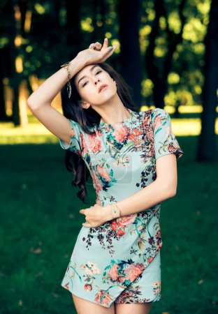 Photo for Beautiful brunette fashionable woman outdoors. Young female model wearing dress posing in summer park. - Royalty Free Image