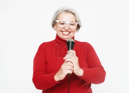 Photo for Lifestyle, hobby and old people concept: Portrait of senior singer woman wearing red sweater on white background - Royalty Free Image