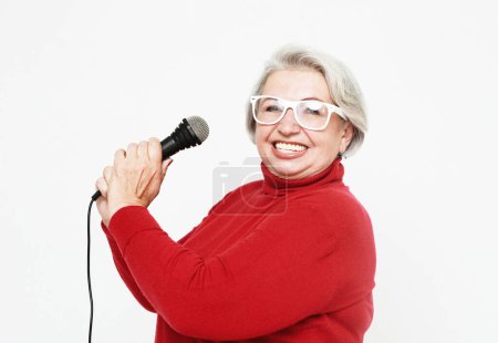 Photo for Emotion, lifestyle and old people concept: Happy senior woman singing with microphone, having fun, expressing musical talent over white background - Royalty Free Image