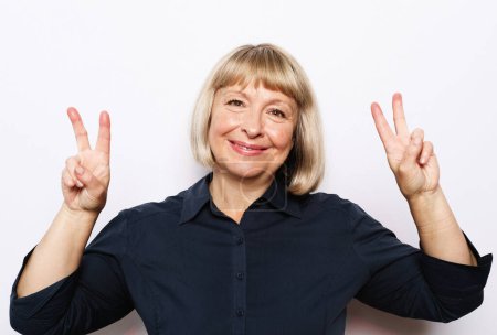 Foto de Portrait of happy senior woman with short blond hair smiling on white background. Lifestyle and emotion concept. - Imagen libre de derechos