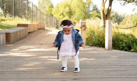 Téléchargez les photos : First steps of little baby girl in summer park. Lifestyle and childhood concept. - en image libre de droit