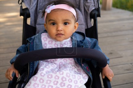 Téléchargez les photos : Pretty baby girl sits in a stroller and laughs loudly, lifestyle and childhood concept. - en image libre de droit