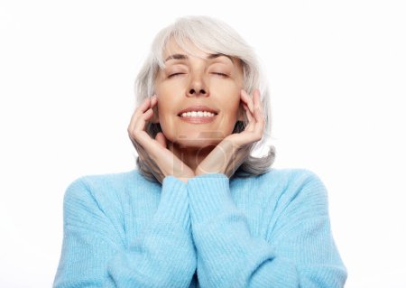 Téléchargez les photos : Heureuse femme âgée portant un pull bleu souriant sur fond blanc, gros plan - en image libre de droit