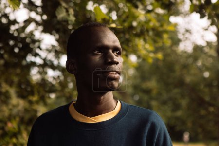 Téléchargez les photos : Portrait extérieur d'un homme noir levant les yeux et portant des vêtements décontractés. - en image libre de droit