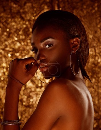 Foto de Retrato de belleza de una atractiva mujer africana semidesnuda con pelo negro corto aislado sobre fondo dorado - Imagen libre de derechos