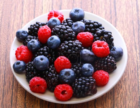 Photo for Blackberries, raspberry and blueberrys on white plate. Close up. - Royalty Free Image